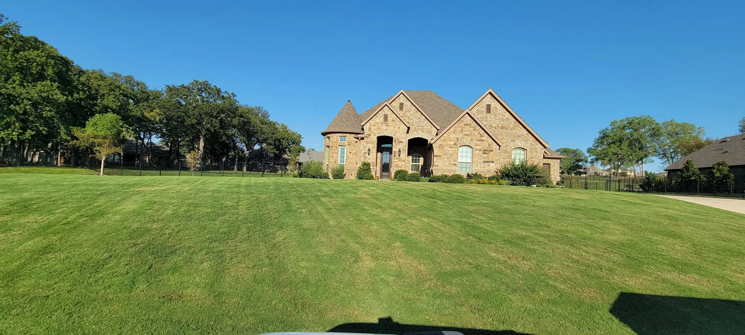 Stone home in North Fort Worth with a freshly mowed and striped front lawn by Watson Landscaping Services
