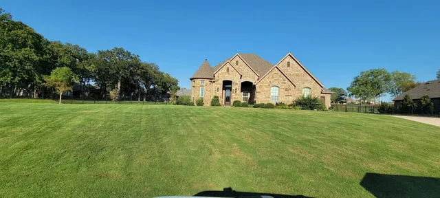 Stone home with a wide, freshly striped front lawn in North Fort Worth