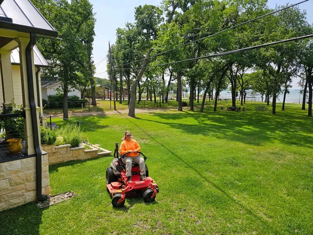 Owner mowing a shaded backyard lawn on a zero-turn mower