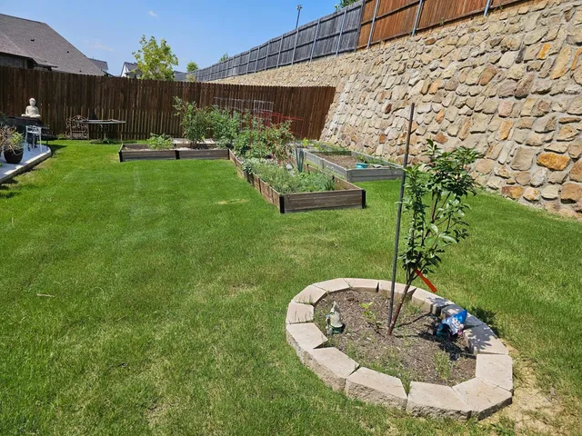 Raised garden bed and stone tree ring installed in a backyard